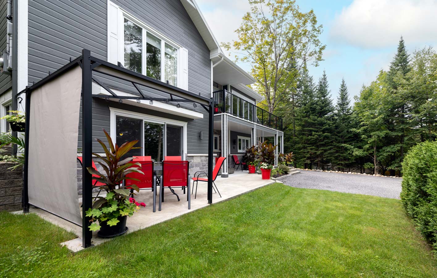 Elegante Terrassenüberdachung aus schwarzem Metall mit Sichtschutz und Sitzgelegenheiten.