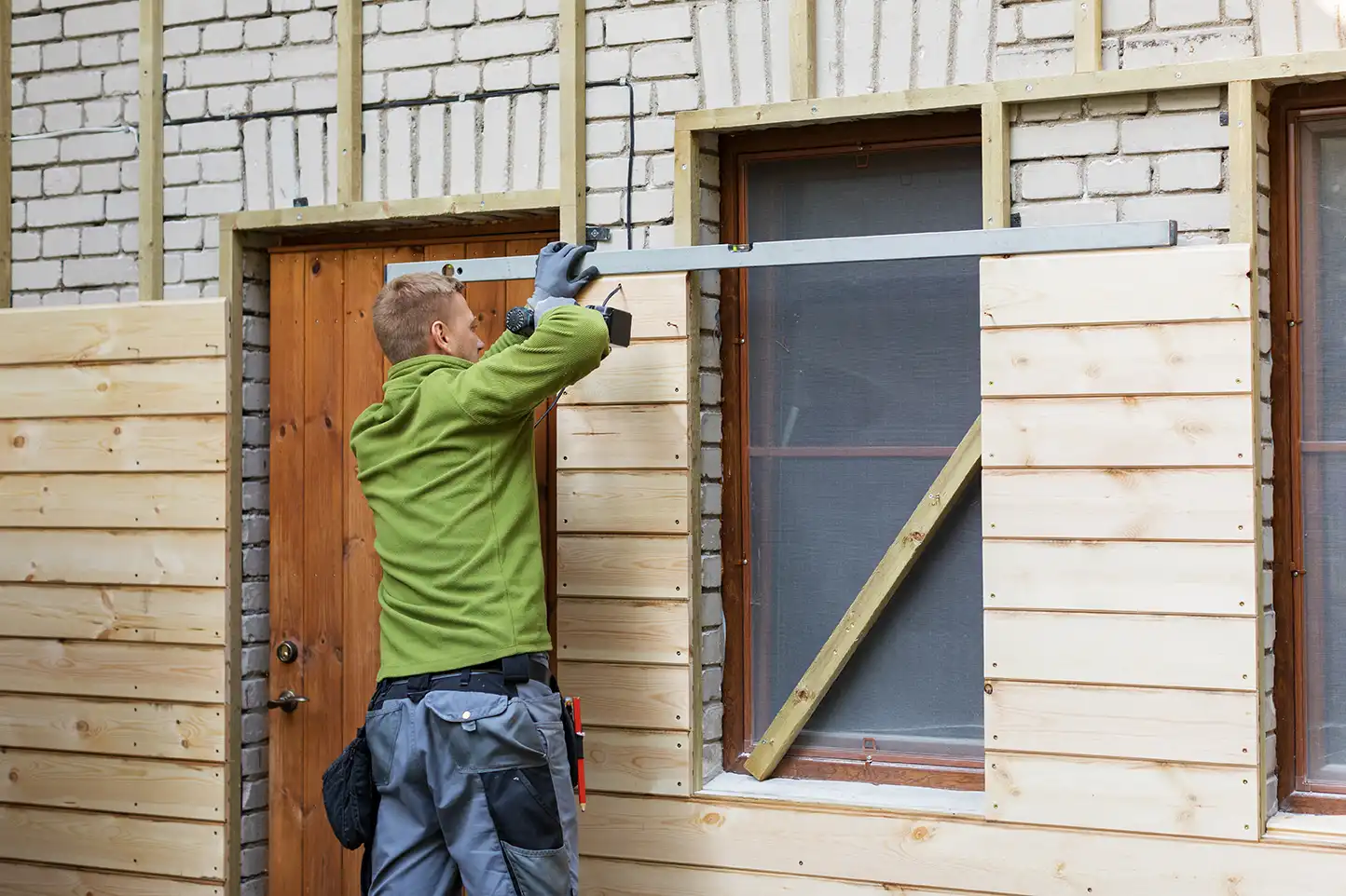 Handwerker montiert Holzfassadenbretter auf einer Unterkonstruktion